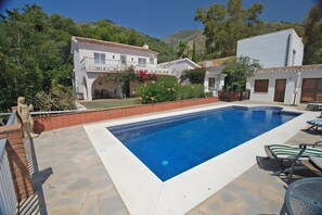 A rectangular swimming pool with a white border, surrounded by a patio area with stone flooring. - Villa 'Secreta' with Sea View, Wi-Fi and Air Conditioning (Mijas)