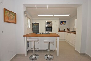 A modern kitchen with white cabinets, a wooden countertop, and two bar stools. - Villa 'Secreta' with Sea View, Wi-Fi and Air Conditioning (Mijas)