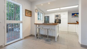 Una cocina moderna con armarios blancos, encimera de madera y dos taburetes de bar.