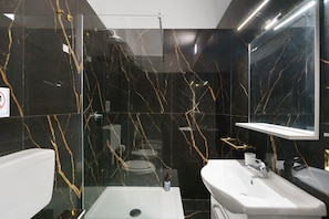 Une salle de bain moderne avec une douche à parois de verre, un lavabo blanc et un miroir au-dessus du lavabo.