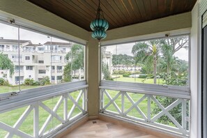 A balcony with white railings, a hanging blue lantern, and a view of a residential area with buildings and greenery.
