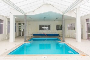 An indoor swimming pool with a tiled floor, a ceiling with recessed lighting, and a bench along the wall. - WI-FI 350MB | Trapiche Lagoa da Conceição #LA12D (Florianópolis)