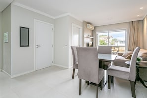 A modern dining area with a table and chairs, a window with a view, and a door. - Wi-Fi 500MB | 150m from the beach | Pool #IA37 (Florianópolis)