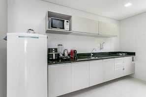 A modern kitchen with white cabinetry, a built-in microwave, a coffee maker, and a toaster. - Wi-Fi 500MB | 150m from the beach | Pool #IA37 (Florianópolis)