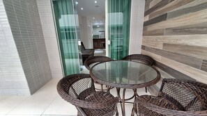 A glass-top round table with wicker chairs in a modern interior space. - O AP mais lindo da Praia do Forte 213 (Cabo Frio)