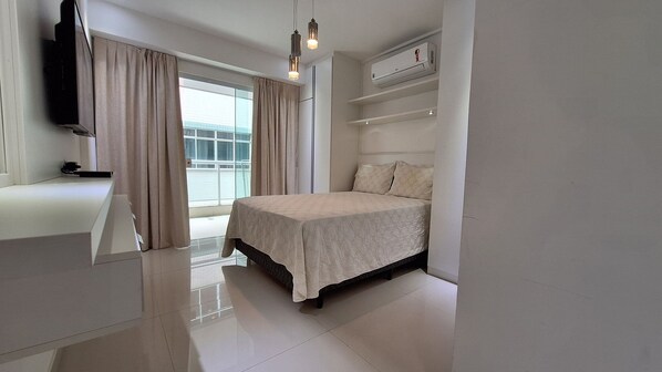 A bedroom with a bed, a TV, a window with curtains, and a balcony. - O AP mais lindo da Praia do Forte 213 (Cabo Frio)
