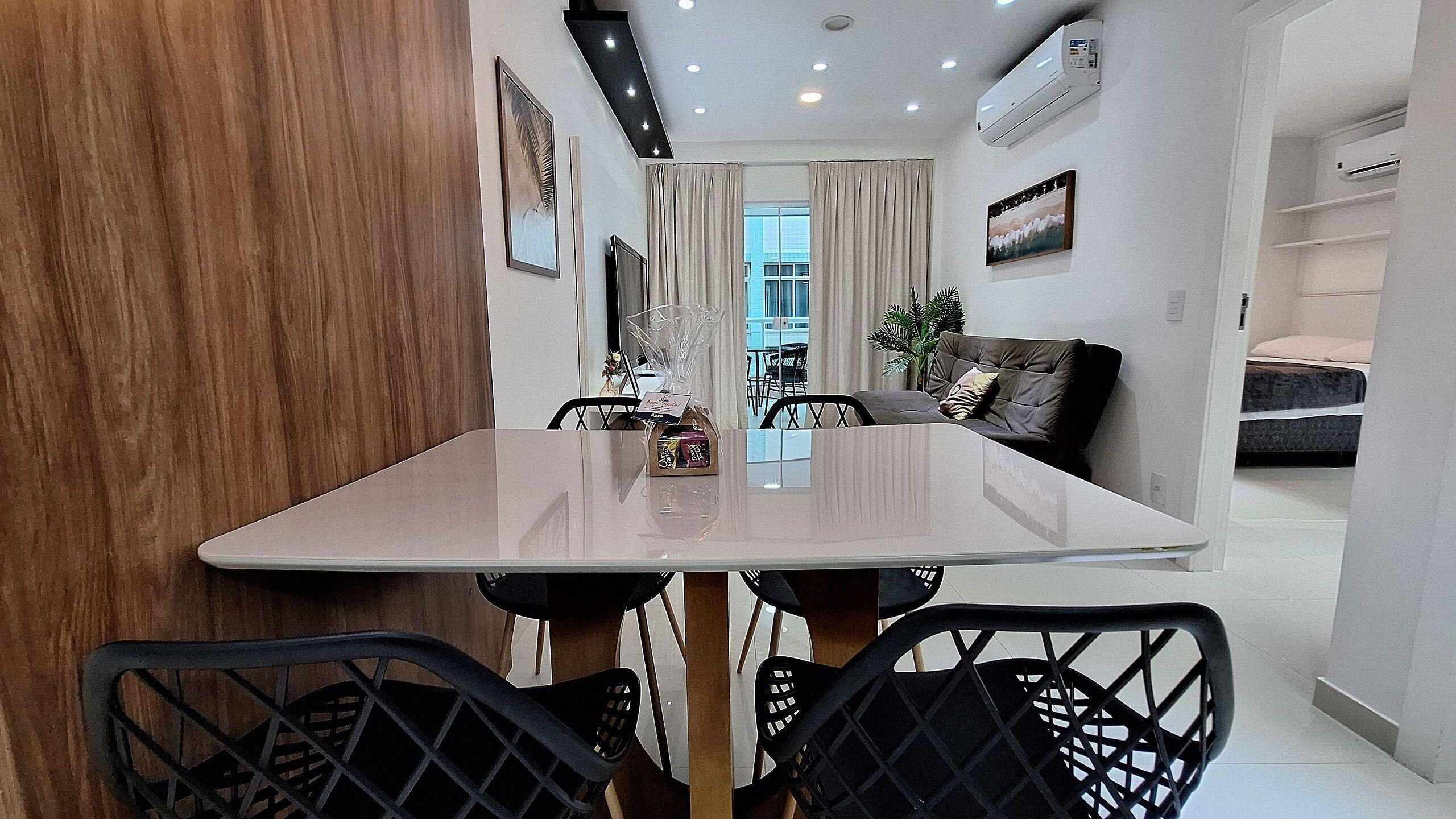 Uma área de refeições moderna com uma mesa, cadeiras e vista para o exterior.