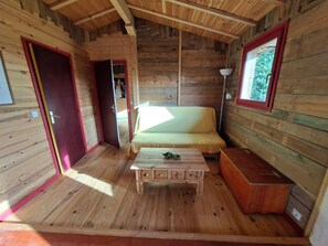 L’intérieur d’un chalet en bois, avec un lit, une table et une lampe.
