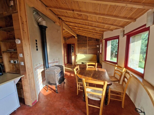 L’intérieur d’un chalet en bois comprend une table à manger, des chaises, un radiateur et une fenêtre donnant sur un paysage agréable.