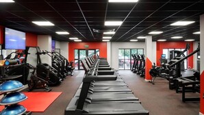 Uma academia com esteiras, bicicletas ergométricas e máquinas de musculação.