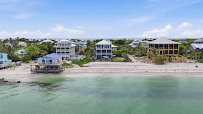 A beachfront property with multiple buildings, including a large two-story house with a balcony and a smaller structure with a deck. - New! Beachfront, Heated Pool, Hot Tub & Golf Carts (North Captiva)