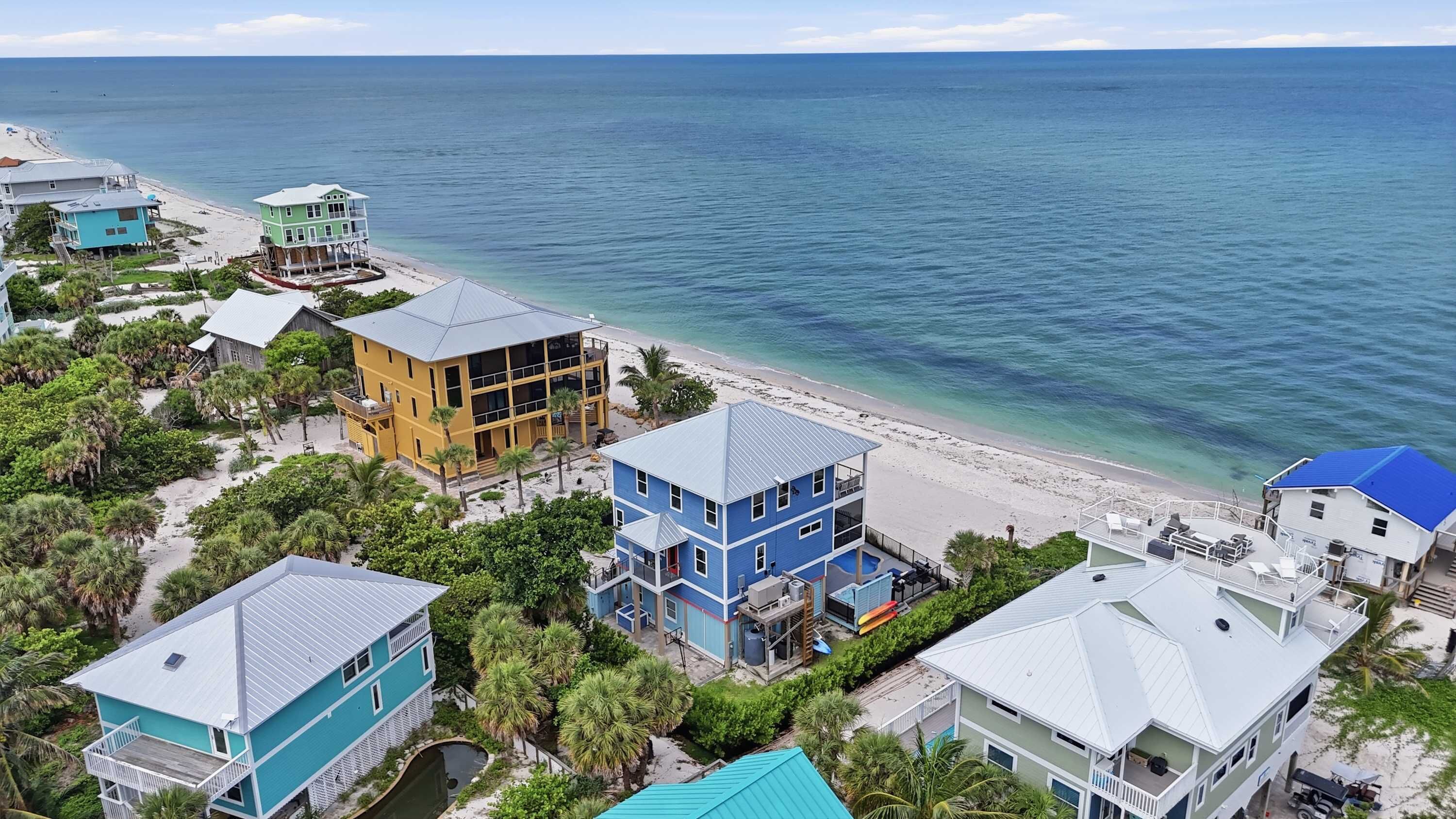 A coastal residential area with multiple houses, a beach, and a clear view of the ocean.