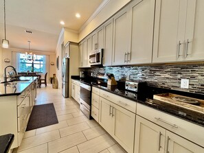 Een moderne keuken met lichte kastjes, een zwart aanrecht en een spatwand met een mozaïektegelpatroon.