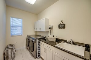 A laundry room with a washing machine, dryer, and a sign indicating it's a laundry room. - Villa 1st Place-Peaceful 3-bedroom house with AC in charming Cape Coral (Cape Coral)