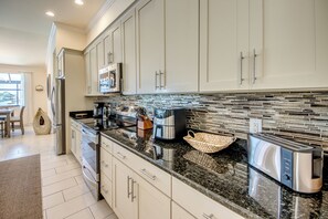 A modern kitchen with stainless steel appliances, a granite countertop, and a backsplash with a mosaic tile design. - Villa 1st Place-Peaceful 3-bedroom house with AC in charming Cape Coral (Cape Coral)