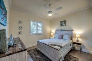 A bedroom with a bed, a ceiling fan, a window with blinds, a wall clock, and a decorative wall piece. - Villa 1st Place-Peaceful 3-bedroom house with AC in charming Cape Coral (Cape Coral)