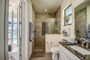 Ein modernes Badezimmer mit Duschabtrennung aus Glas, Toilette und Waschbecken mit Granitplatte.