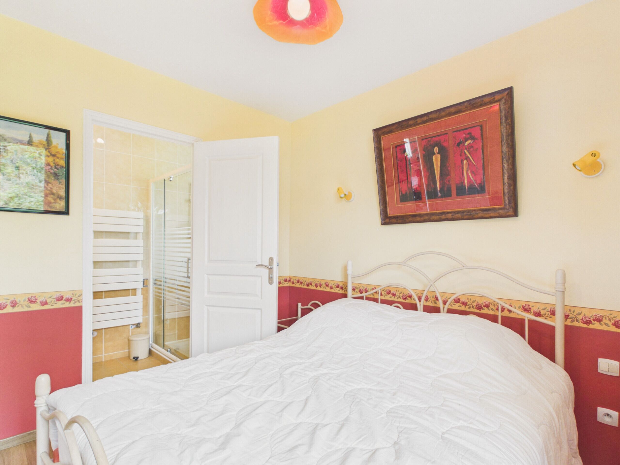 A bedroom with a bed, a door, a framed picture, and a window.