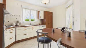 A modern kitchen with a dining area, including a stove, sink, cabinets, and a dining table with chairs. - Beach at 200m, family house for 7 with garden (Plouguerneau)