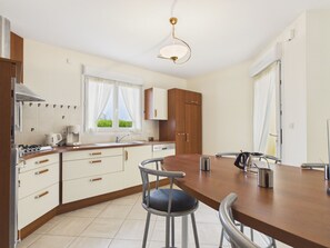 A modern kitchen with a dining area, including a stove, sink, cabinets, and a dining table with chairs. - Near beach, spacious house with garden (Plouguerneau)