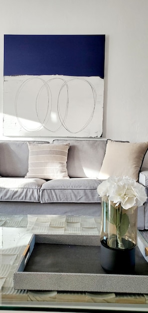 Ein modernes Wohnzimmer mit einer Couch, einem Couchtisch und einer dekorativen Vase mit Blumen.