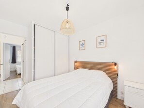 Ein Schlafzimmer mit einem Bett, einer Hängelampe und zwei gerahmten Bildern an der Wand.