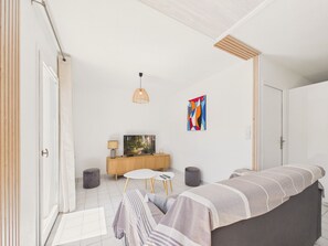 Ein modernes Wohnzimmer mit einer Couch, einem Fernseher, einem Beistelltisch, einer Lampe und einem farbenfrohen abstrakten Gemälde.