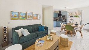 Un salon moderne avec un canapé vert, une table basse et un coin repas comprenant une table et des chaises.