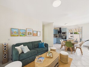 Ein modernes Wohnzimmer mit einem grünen Sofa, einem Couchtisch und einem Essbereich mit Tisch und Stühlen.