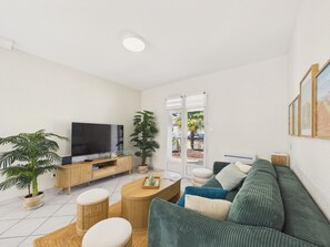 Un saló modern amb televisió de pantalla plana, sofà, taula de centre i una gran planta en test.