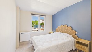 Une chambre à coucher avec un lit, une table de chevet, une fenêtre et un radiateur.