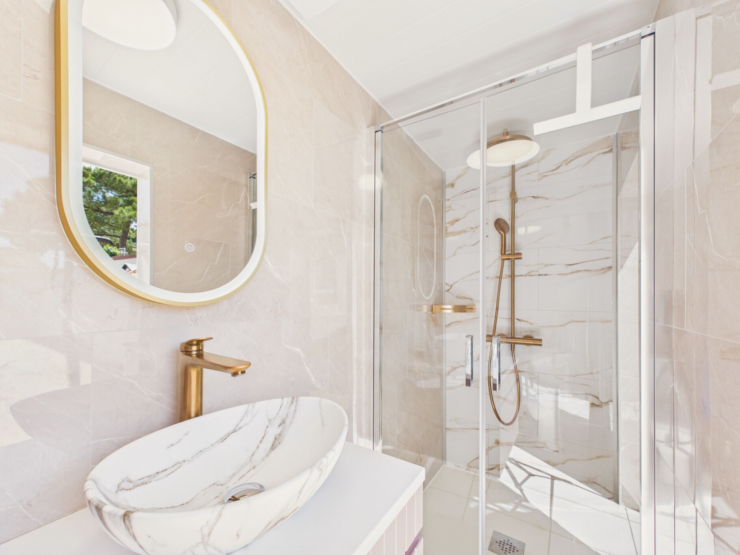 A modern bathroom with a marble sink, a large mirror, and a glass-enclosed shower.