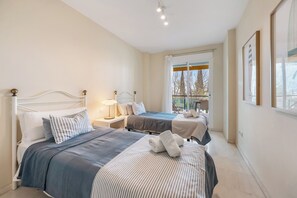 Ein Hotelzimmer mit zwei Betten, einem Fenster mit Blick und einem gerahmten Bild an der Wand.