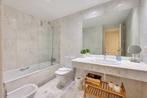 Et moderne badeværelse med badekar, toilet og bruser.
