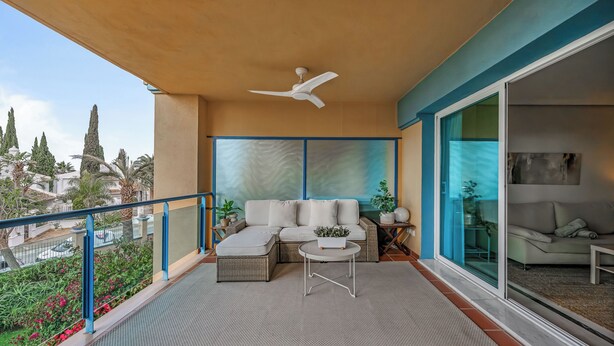 Ein Balkon mit einer Couch, einem kleinen Tisch und einem Deckenventilator.