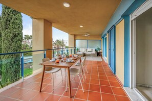 En balkon med et spisebord til fire personer, en sofa og en ventilator i loftet.