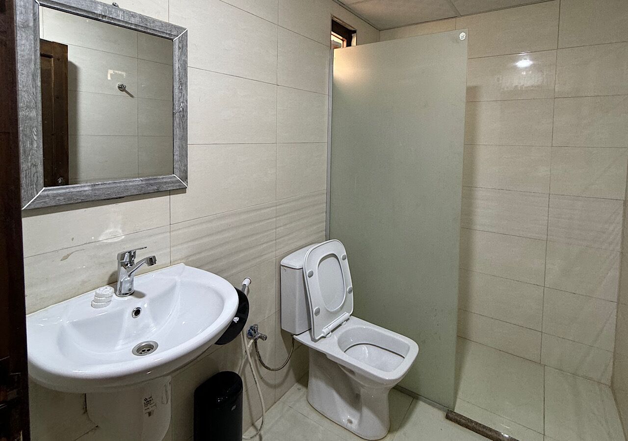 A bathroom with a white sink, mirror, and toilet.