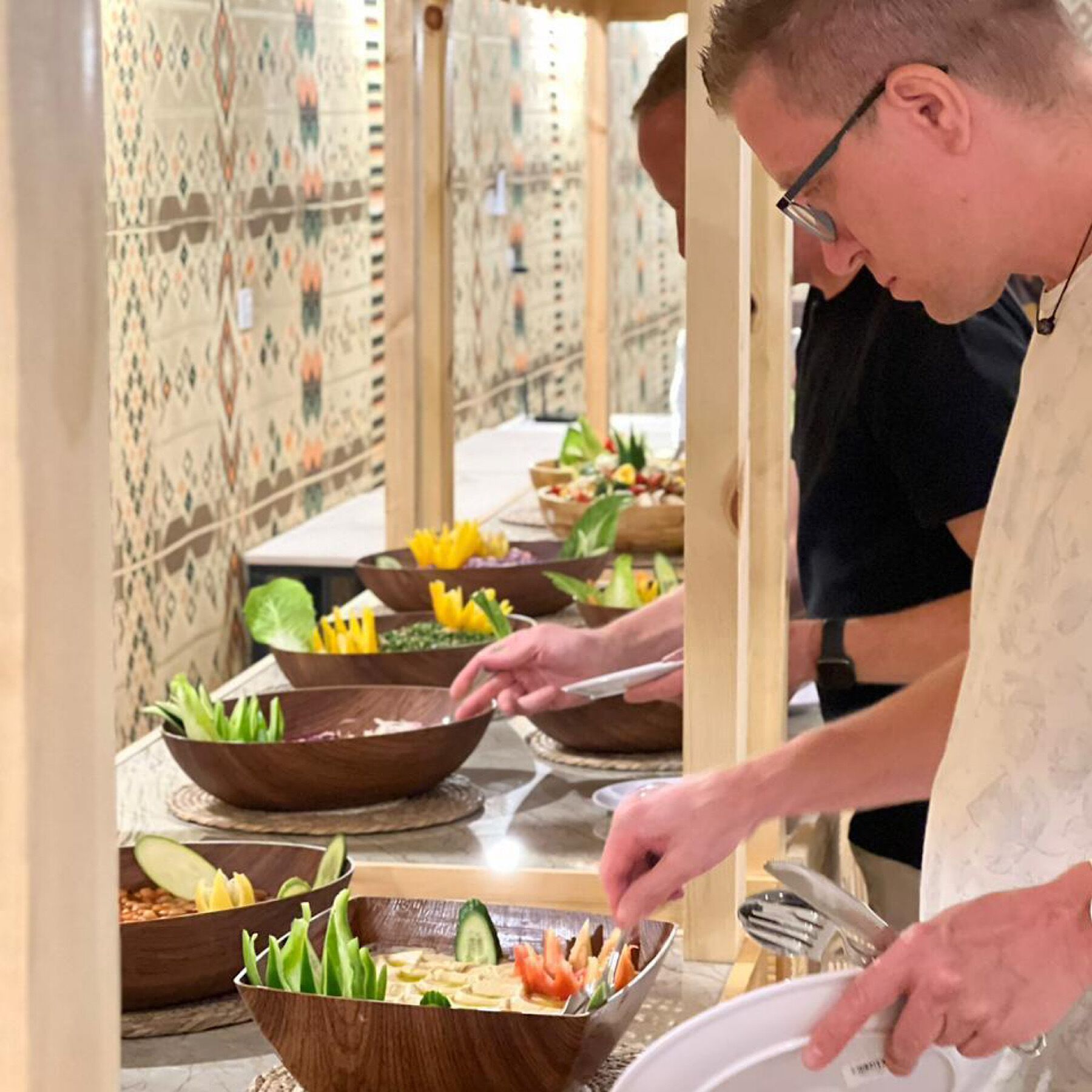 A buffet setup with various dishes and a person serving food.