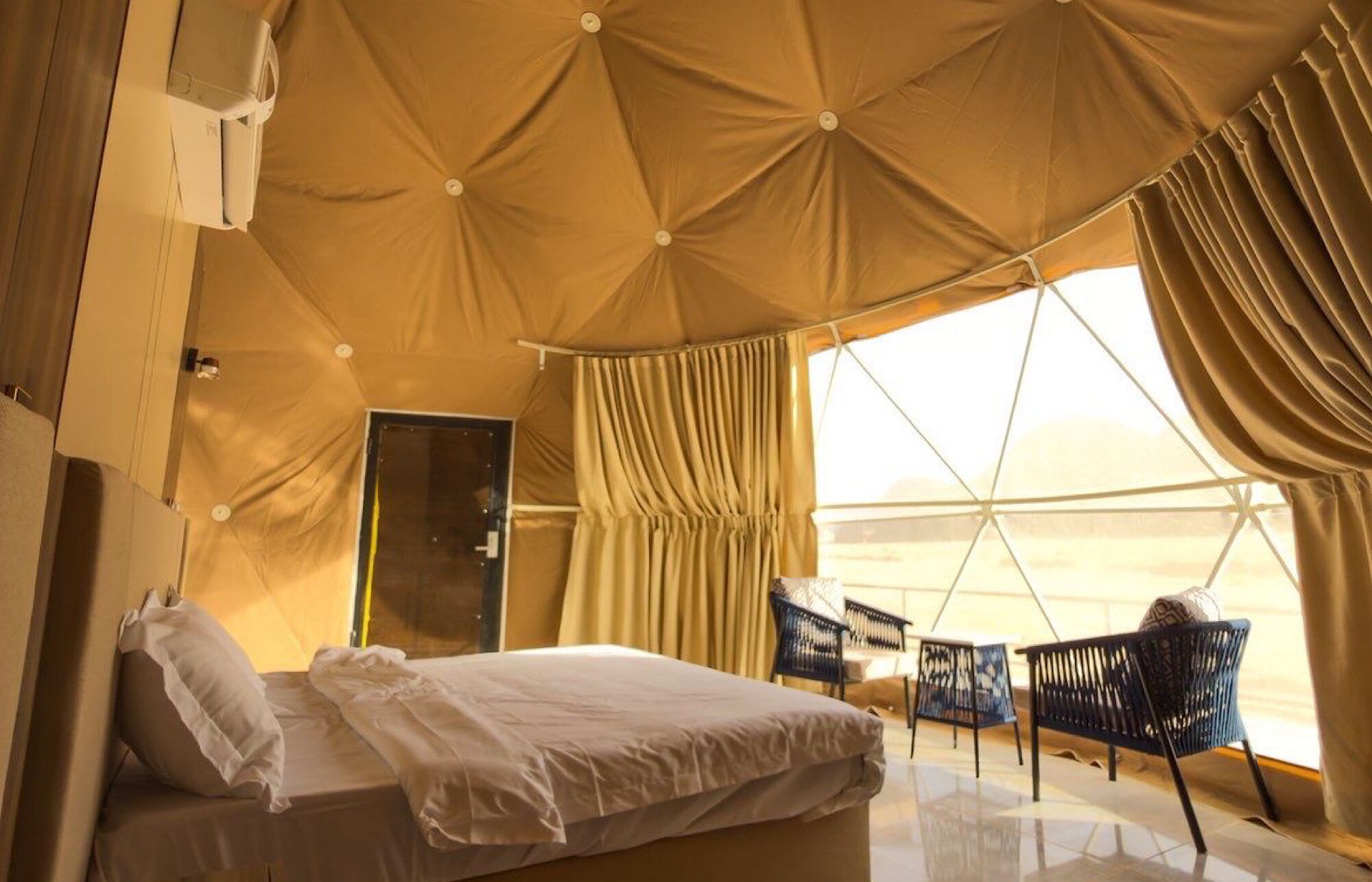 Habitació tipus tenda amb un llit, una cadira i una finestra.