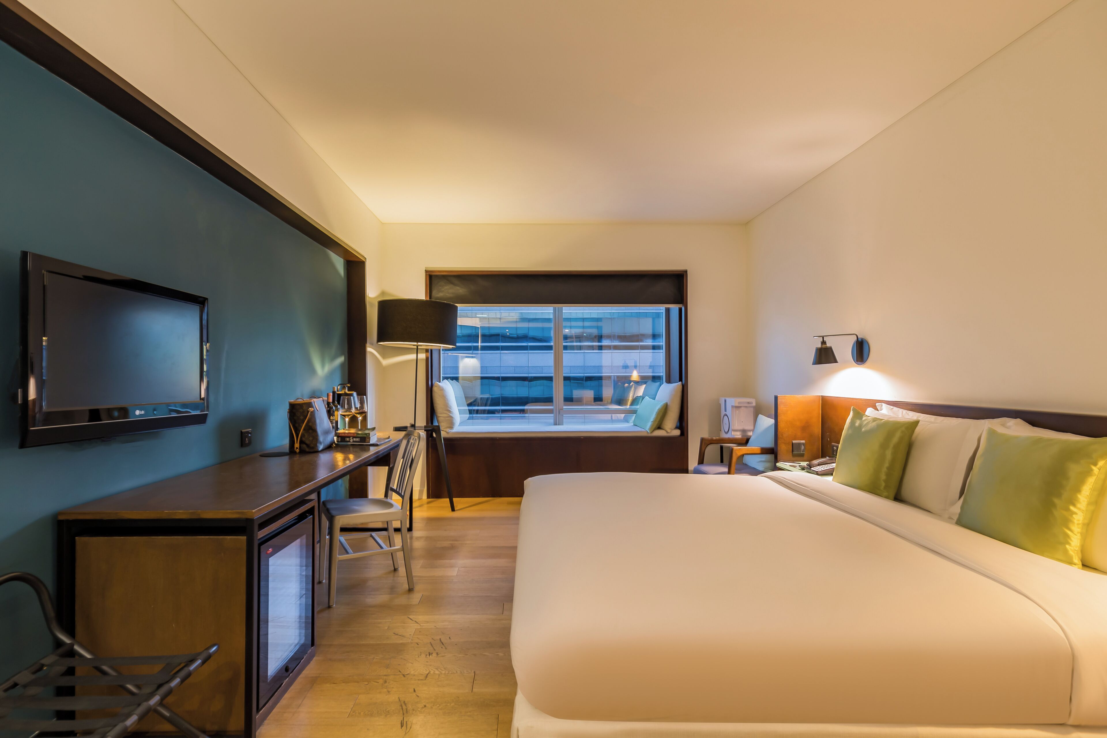 A hotel room with a bed, desk, television, and a window with a view.
