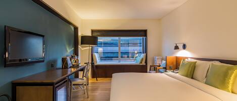 A hotel room with a bed, desk, television, and a window with a view.
