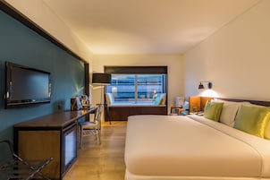 Ein Hotelzimmer mit Bett, Schreibtisch, Fernseher und einem Fenster mit Blick.