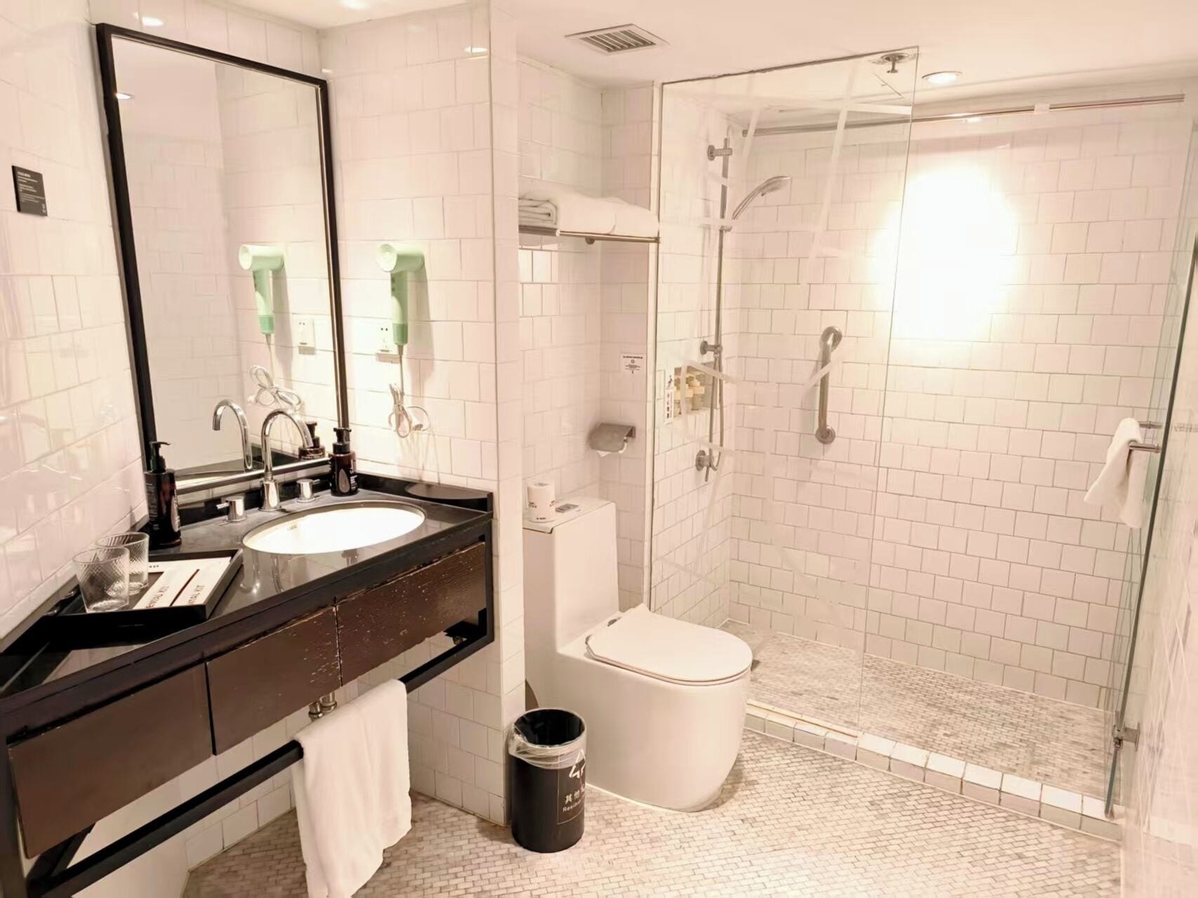 A modern bathroom with a sink, mirror, toilet, and glass-enclosed shower.
