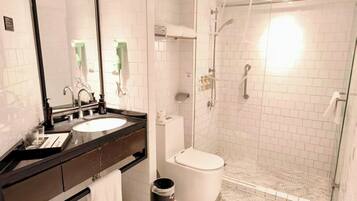 A modern bathroom with a sink, mirror, toilet, and glass-enclosed shower.
