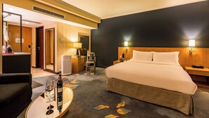 Ein Hotelzimmer mit Bett, Nachttisch, Lampe, Stuhl und Schreibtisch mit Sitzgelegenheit.