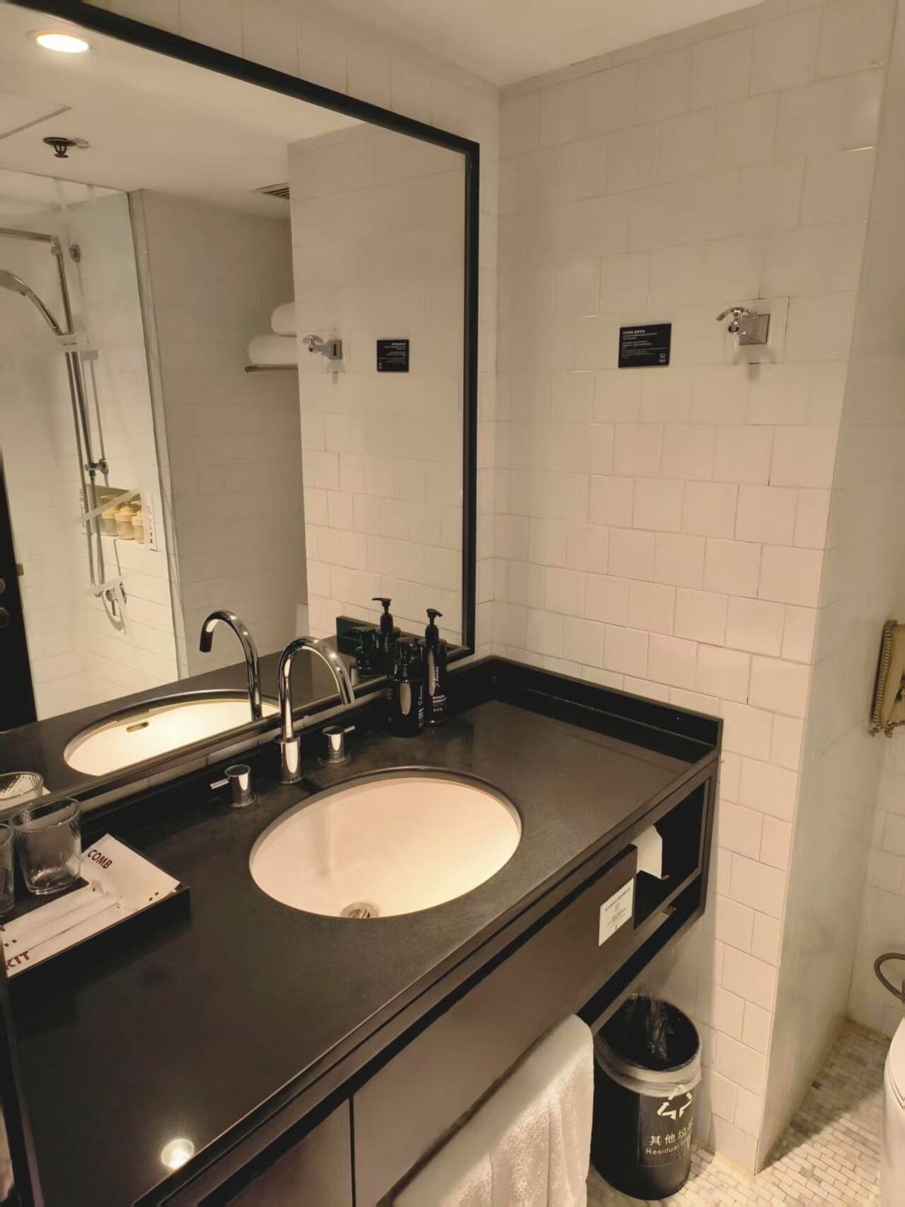 A modern bathroom with two sinks, a large mirror, and a towel rack.
