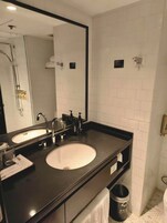 A modern bathroom with two sinks, a large mirror, and a towel rack.