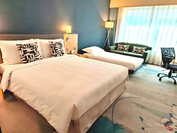 Una habitación de hotel con dos camas, un sofá verde, un escritorio y una silla.