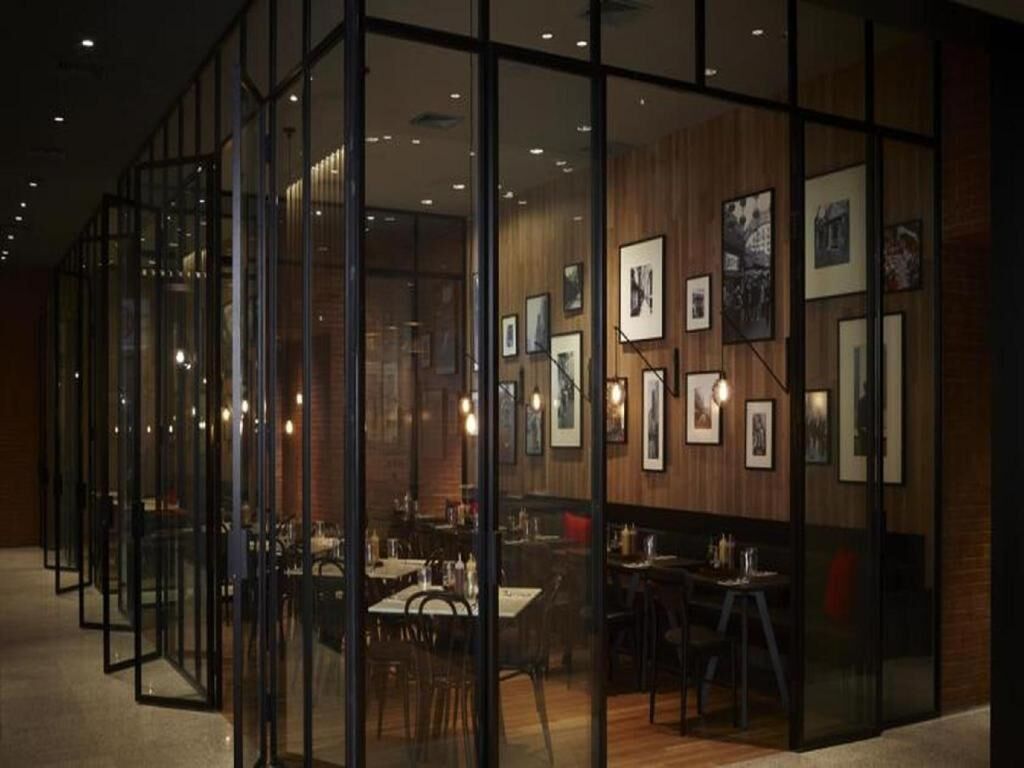A modern interior with glass partitions, wooden paneling, and framed artwork on the walls.