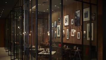 A modern interior with glass partitions, wooden paneling, and framed artwork on the walls.